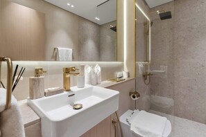 Un baño moderno con un lavamanos grande, un espejo, una ducha y un inodoro.