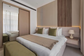 A hotel room with a large bed, a bedside table with a lamp, a mirror, and a view of the outside. - Stylish 1BR Dubai with Pool, Gym, Padel & Balcony (Jumeirah Village Circle)