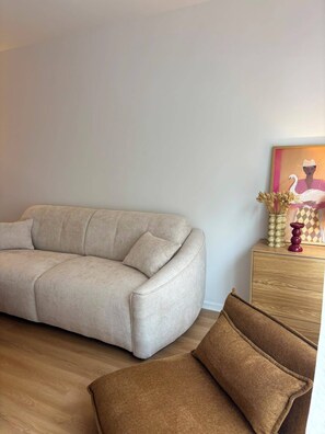 Ein Wohnzimmer mit einer Couch, einem braunen Sessel, einem Holztisch mit Dekoration und einem Bild an der Wand.