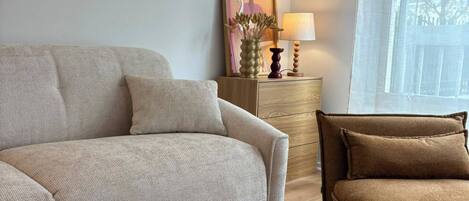A living room with a sofa, a smaller couch, a round coffee table, and a side table with a lamp.