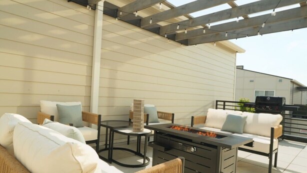 Eine Terrasse im Freien mit Feuerstelle, Sitzgelegenheiten und Grillbereich.