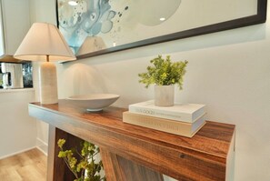 A wooden console table with a bowl, a potted plant, and books. - Downtown Skyline Views | Rooftop Patio | Sleeps 7+ (Des Moines)