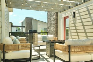 Eine Terrasse im Freien mit Korbmöbeln, einem Grill und einer Steinmauer.