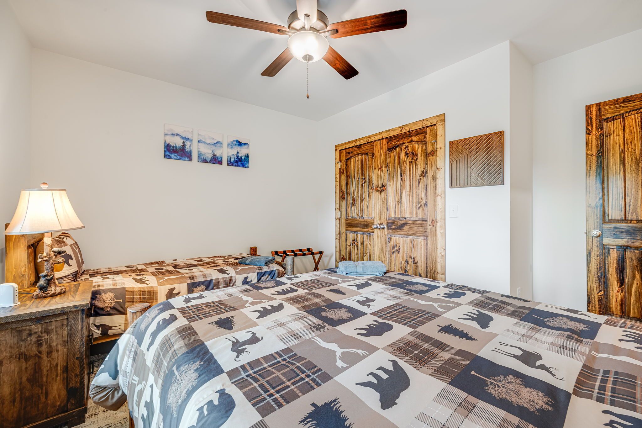 A bedroom with a large bed, a ceiling fan, and wooden doors.