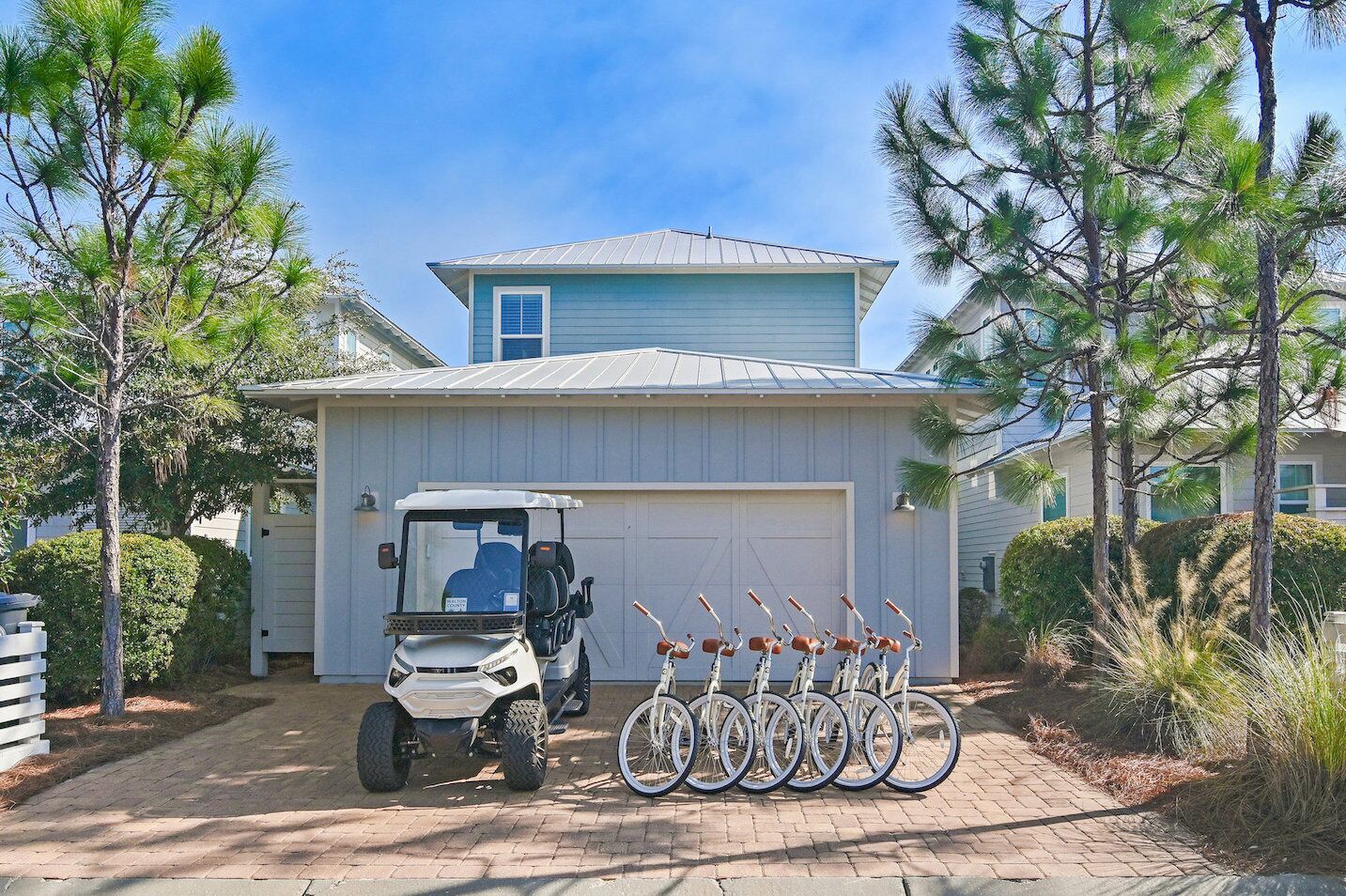 Ein Haus mit Garage, einem Golfwagen und einer Reihe von Fahrrädern, die draußen geparkt sind.