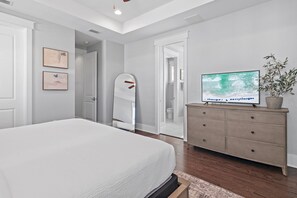 Ein Schlafzimmer mit einem großen Bett, einem Schminktisch, einem Spiegel und einem Fernseher.