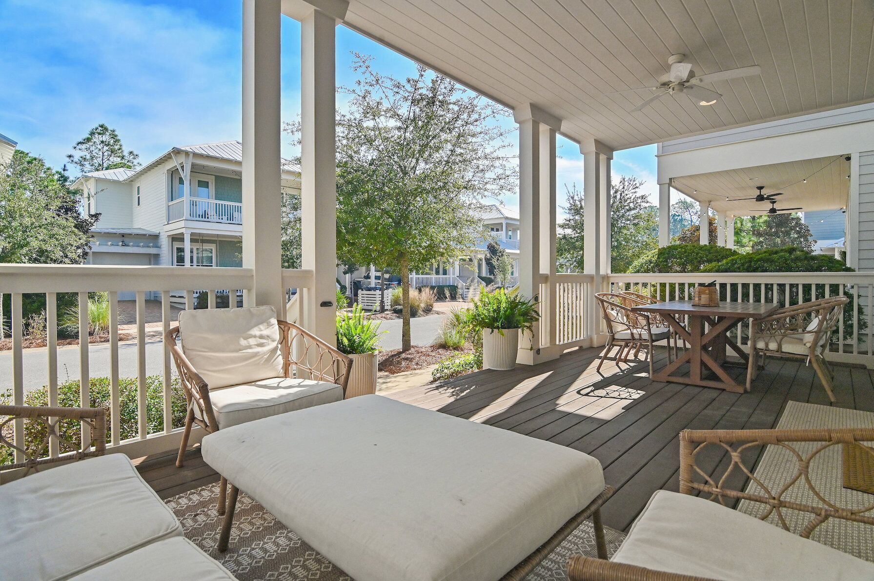 A covered outdoor area with wicker furniture, a table, and potted plants.