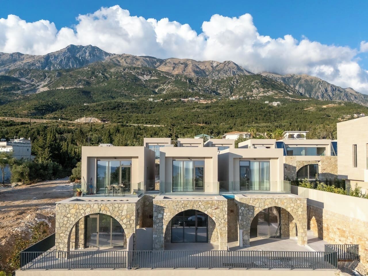 A modern building with multiple levels, large glass windows, and a stone archway entrance.