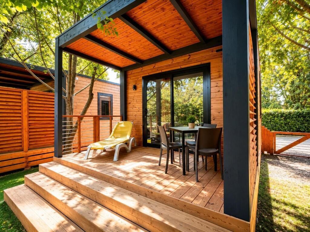 Een houten terras met een tafel en stoelen, een gele stoel en een trap naar een overdekt gedeelte.