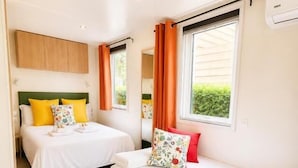 Ein Hotelzimmer mit zwei Betten, einem kleinen runden Tisch und einem Fenster mit Vorhängen.