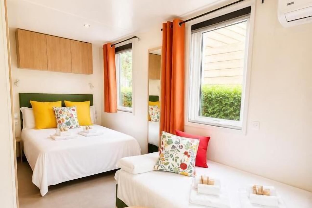 Ein Hotelzimmer mit zwei Betten, einem kleinen runden Tisch und einem Fenster mit Vorhängen.