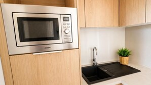 A kitchen with a built-in microwave, a sink, and wooden cabinets.