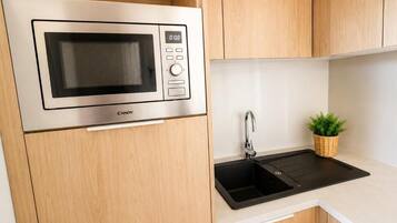 Una cocina con microondas integrado, un fregadero y armarios de madera.