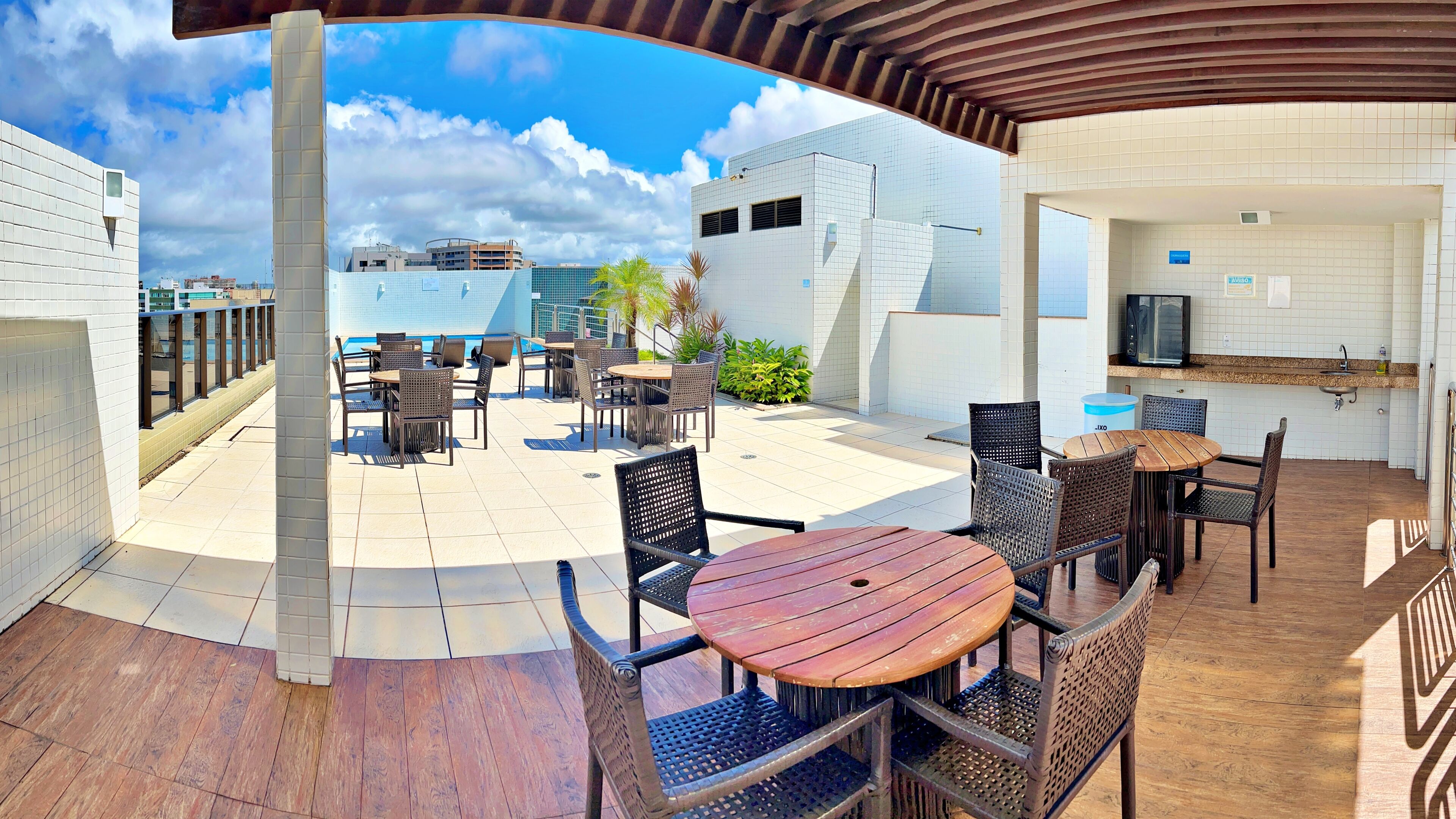 An outdoor patio area with tables and chairs, a pool, and a view of buildings in the background.