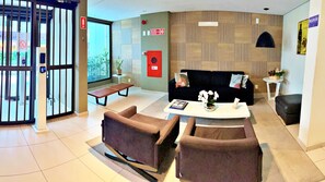 A modern lobby with a reception desk, seating area, and a large window. - MF102 | 3-bedroom, 3-bathroom apartment near Ponta Verde beach (Maceió)