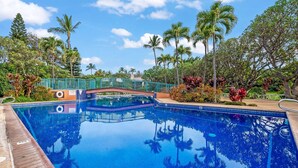 A swimming pool with a bridge, surrounded by palm trees and tropical plants. - Koa Resort 3E | Two Bedroom Condo in Kihei (Kihei)