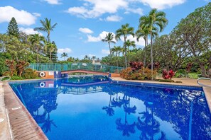 A swimming pool with a bridge, surrounded by palm trees and tropical plants. - Koa Resort 3E | Two Bedroom Condo in Kihei (Kihei)