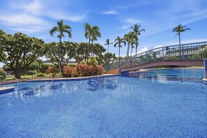 A swimming pool with a bridge, surrounded by palm trees and a clear sky. - Koa Resort 3E | Two Bedroom Condo in Kihei (Kihei)