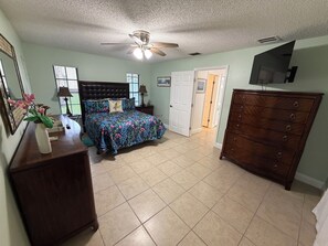 A bedroom with a bed, dresser, TV, and a ceiling fan. - Peaceful 2/2 in Homosassa Springs Hot Spot (Homosassa Springs)
