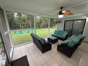 A covered outdoor seating area with wicker furniture and a view of a grassy yard. - Peaceful 2/2 in Homosassa Springs Hot Spot (Homosassa Springs)