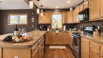 A modern kitchen with wooden cabinets, a stainless steel stove, and a wooden countertop with a cheese board.