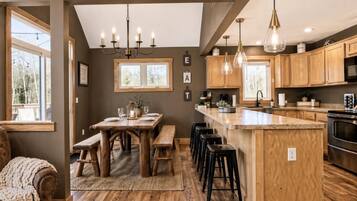 A modern kitchen with wooden cabinetry, a central island, bar stools, and pendant lighting.