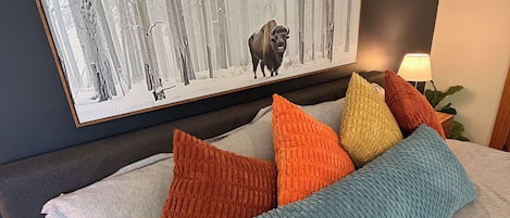 A bed with a gray bedspread and multiple colorful pillows.