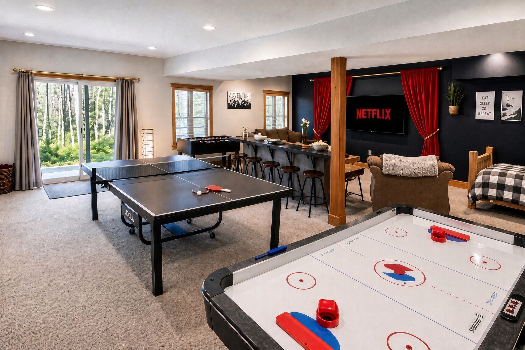 Een kamer met een tafeltennistafel, een tafelvoetbaltafel en een televisiescherm waarop 'NETFLIX' staat.