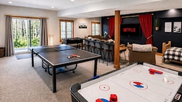Een kamer met een tafeltennistafel, een tafelvoetbaltafel en een televisiescherm waarop 'NETFLIX' staat.