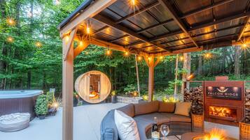 Un espace extérieur accueillant avec des sièges confortables, un jacuzzi, une structure en bois et un foyer.
