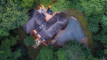 A house surrounded by dense forest with a visible patio area and a swimming pool.