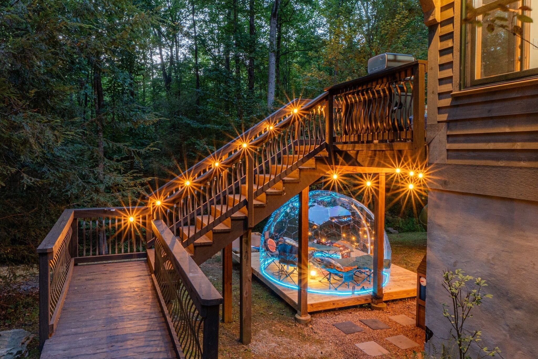 A wooden staircase with railings, leading to a glass-enclosed area with a view of the outdoors.