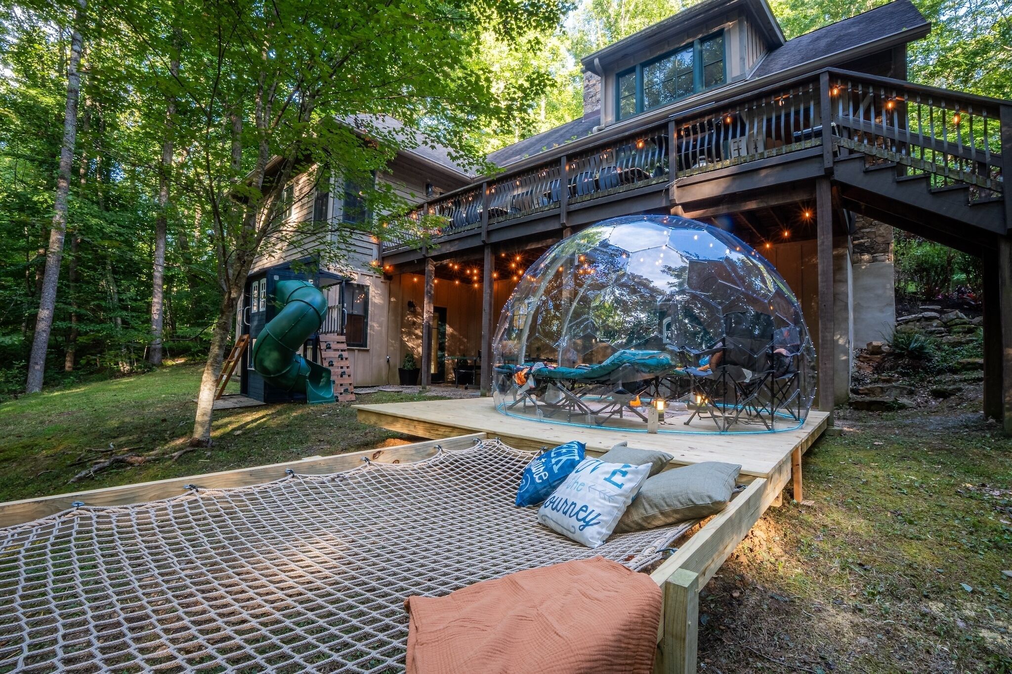 Ein Haus mit einer großen Glaskuppel, einer Rutsche und einer Hängematte.