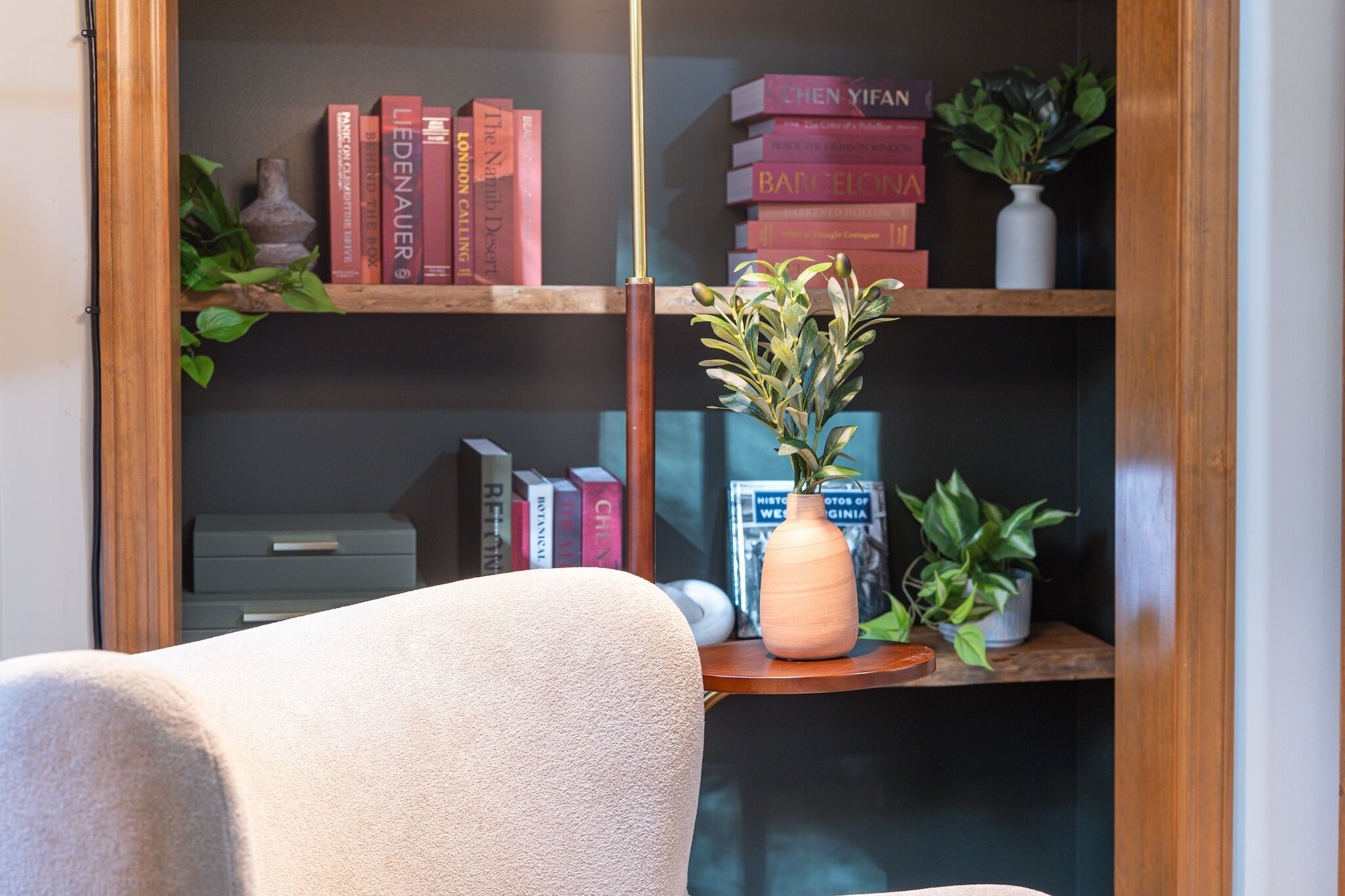 A bookshelf with books and a vase with plants.