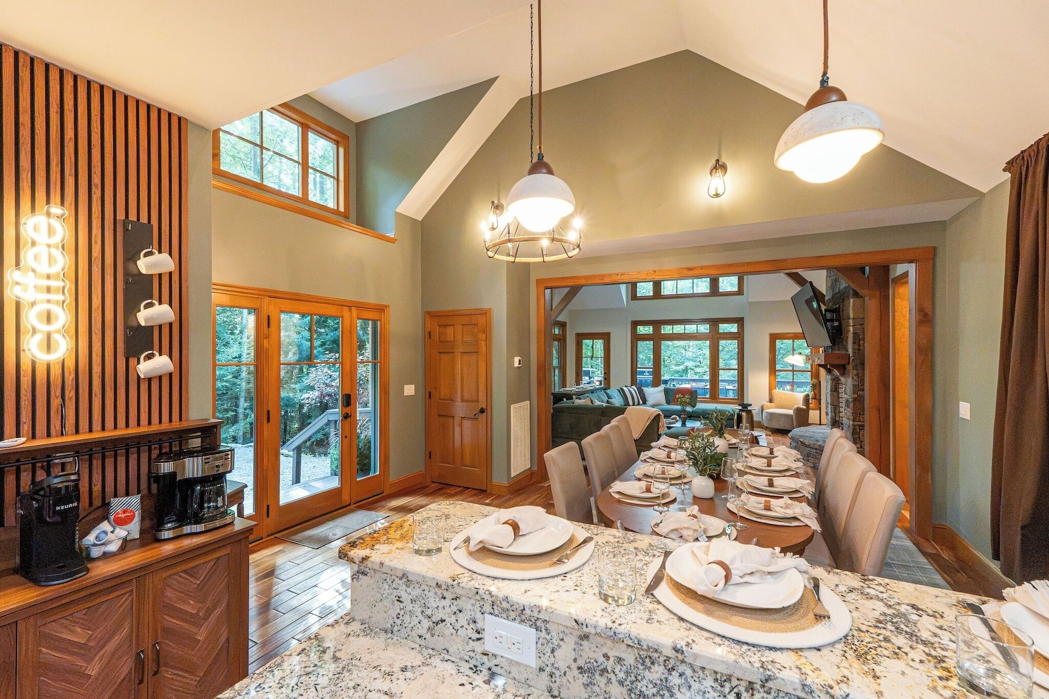 A spacious dining area with a long table set for a meal, wooden cabinetry, and a coffee station.