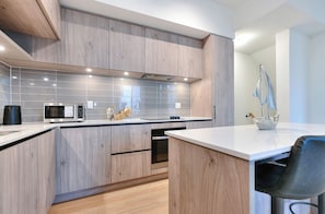 Eine moderne Küche mit Holzschränken, einer Mikrowelle und einem Spülbecken.