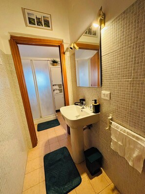Ein Badezimmer mit Waschbecken, Spiegel und Handtuchhalter. Eine Tür führt in einen anderen Raum.