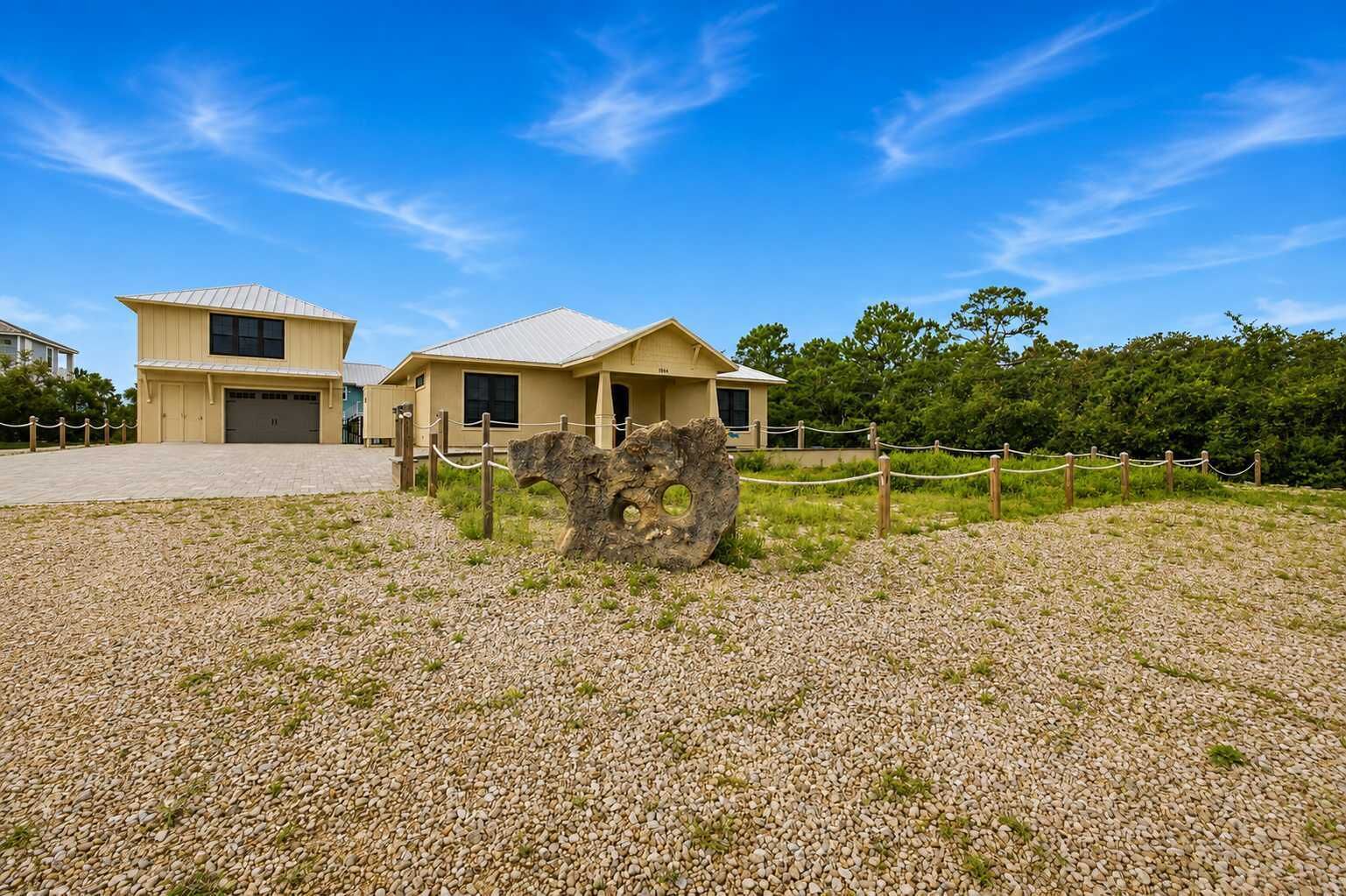 A building with a gravel driveway and a large rock feature in the foreground.