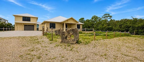 A building with a gravel driveway and a large rock feature in the foreground.