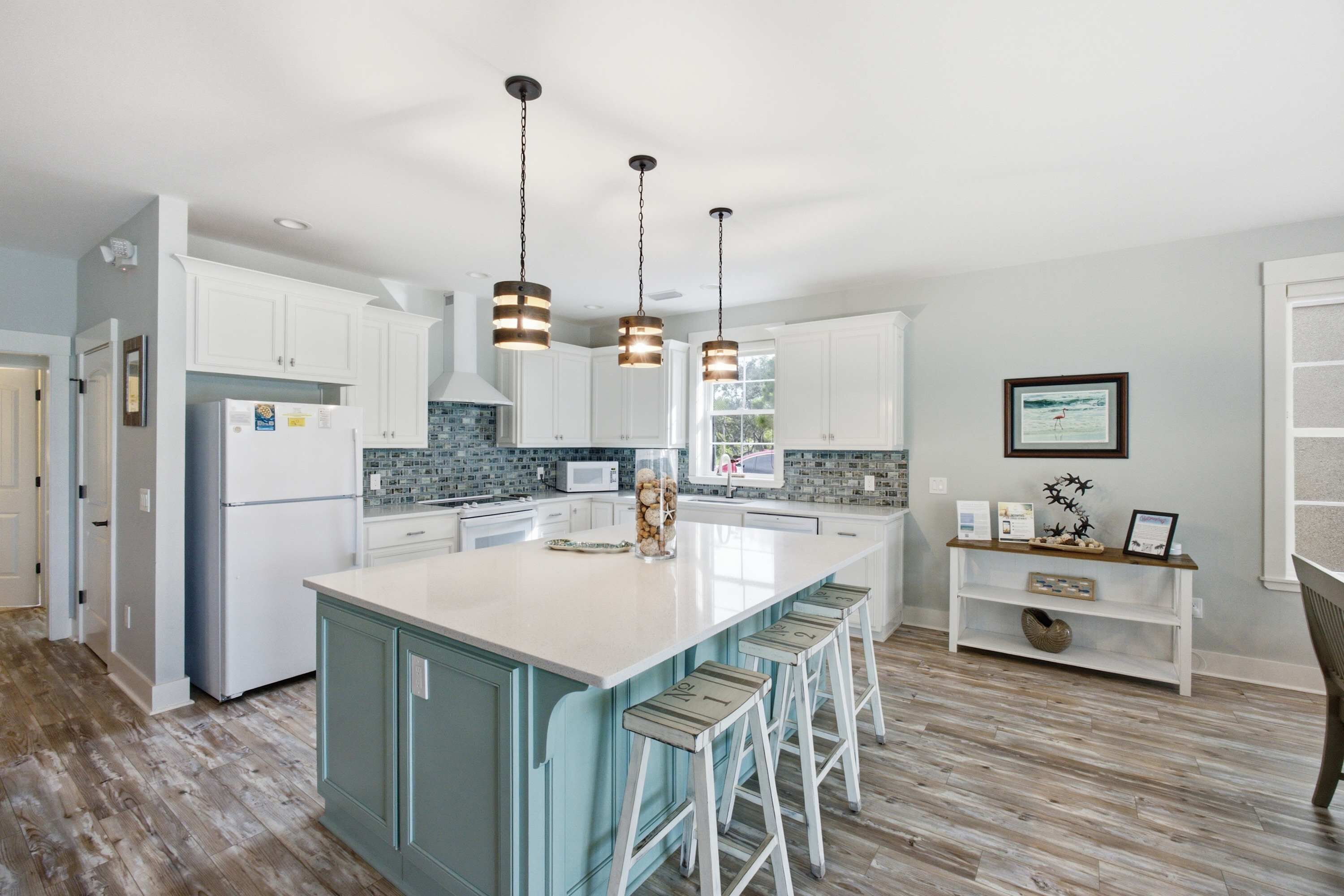 A kitchen with white cabinets, a central island with bar stools, and pendant lighting.