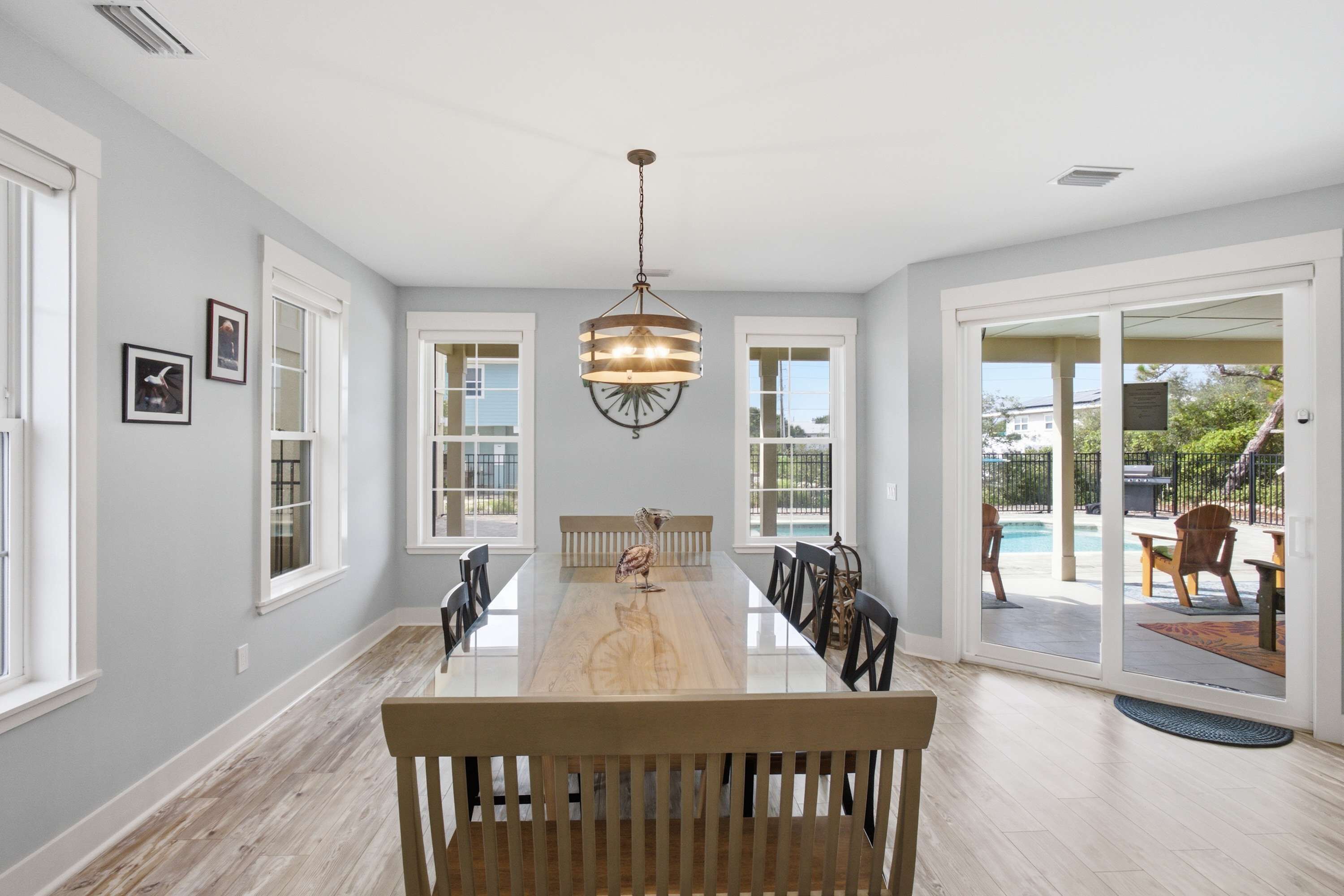A spacious dining area with a long table, chairs, and a hanging light fixture.