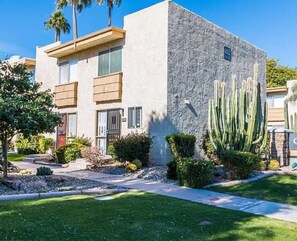 A modern two-story building with a stone facade, a cactus garden, and a well-maintained lawn. - Scottsdale Condo, Pool, Patio & Old Town Views (Scottsdale)