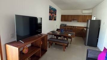 A modern living room with a flat-screen TV, wooden entertainment unit, and a sofa with colorful cushions.