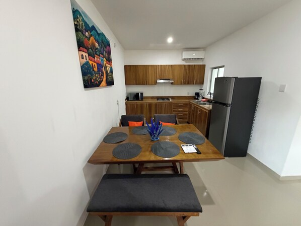 Una cocina moderna con armarios de madera, un refrigerador negro y una mesa de comedor con un banco.