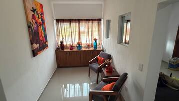 A compact living space with a kitchenette, a dining area with a sofa and chairs, and a large window with curtains.