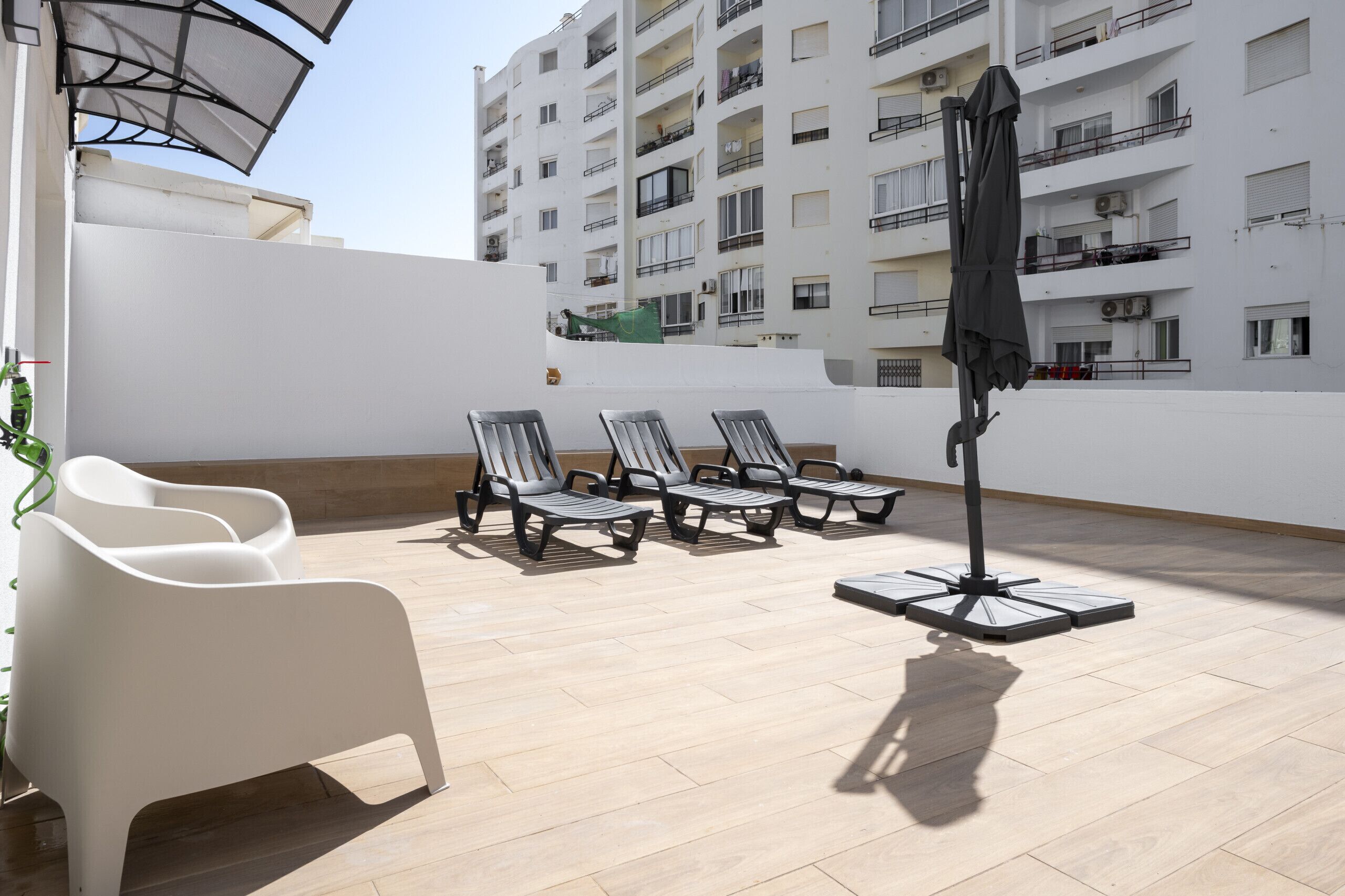 Eine Dachterrasse mit Lounge-Möbeln, einem Tisch und Sonnenschirm.