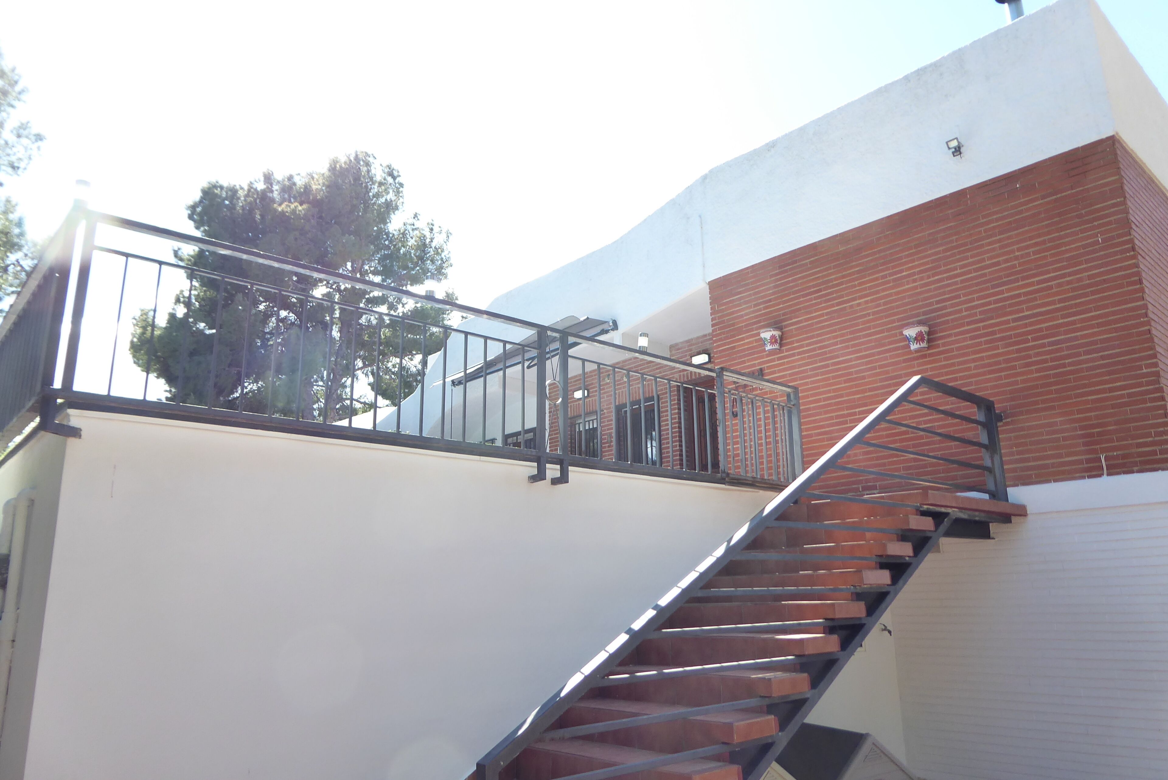 Un escalier avec des rampes en métal menant à un bâtiment à la façade en briques.