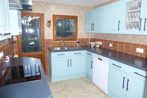 Cocina con alacenas azul claro, encimera negra y ventana con vista a árboles.
