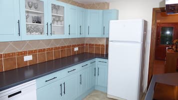 Een keuken met lichtblauwe kastjes, een witte koelkast en een backsplash met bruin patroon.