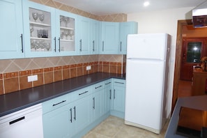 A kitchen with light blue cabinets, a white refrigerator, and brown patterned backsplash.